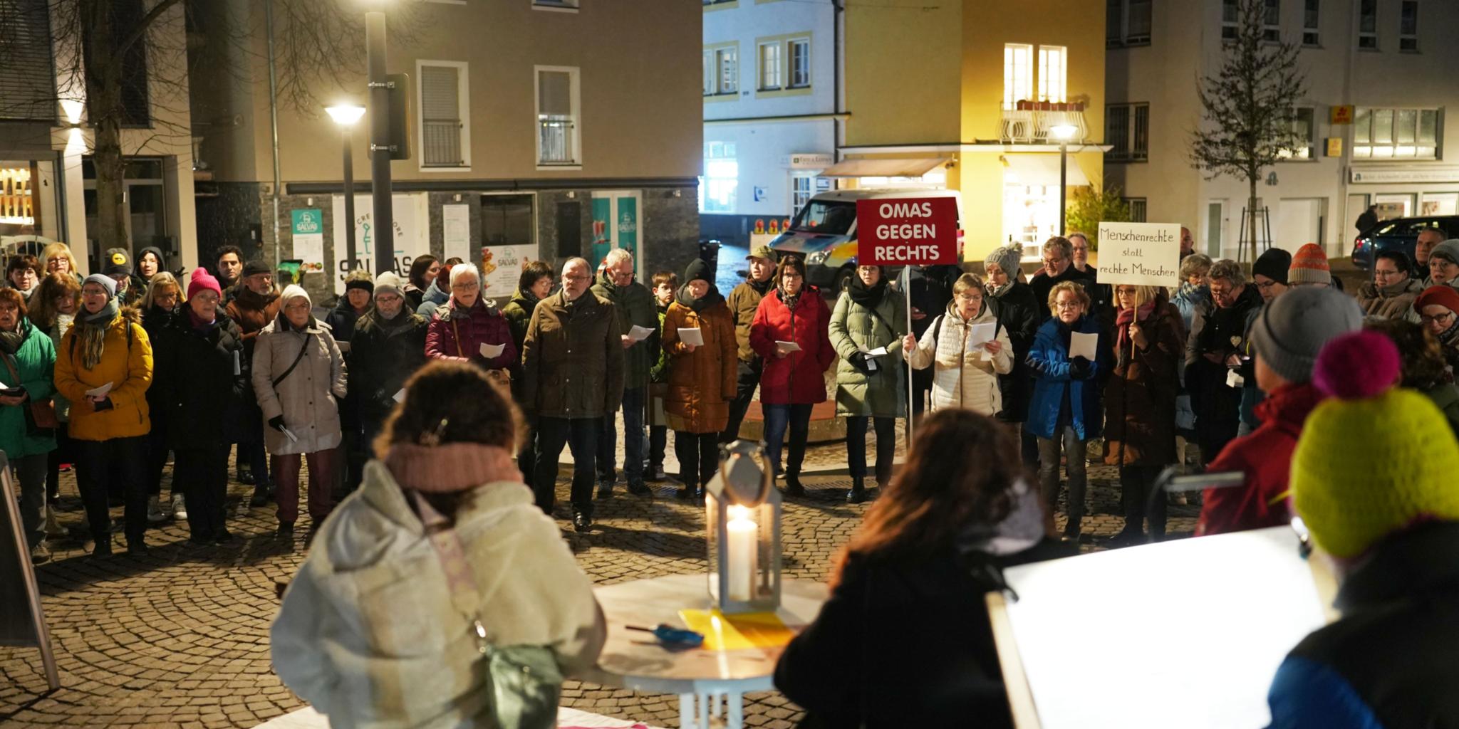 An dem offenen Singen und Beten auf dem Platz an der Lieser haben sich rund 100 Menschen beteiligt – einige auch mit Transparenten.