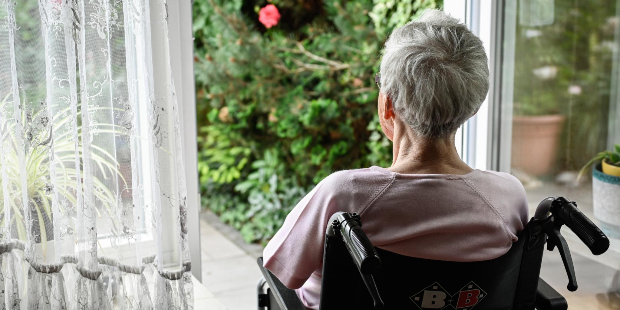 Eine Seniorin schaut in den Garten: Eine Atmosphäre, die ganz bestimmt zu ihrem Wohlbefinden beiträgt.