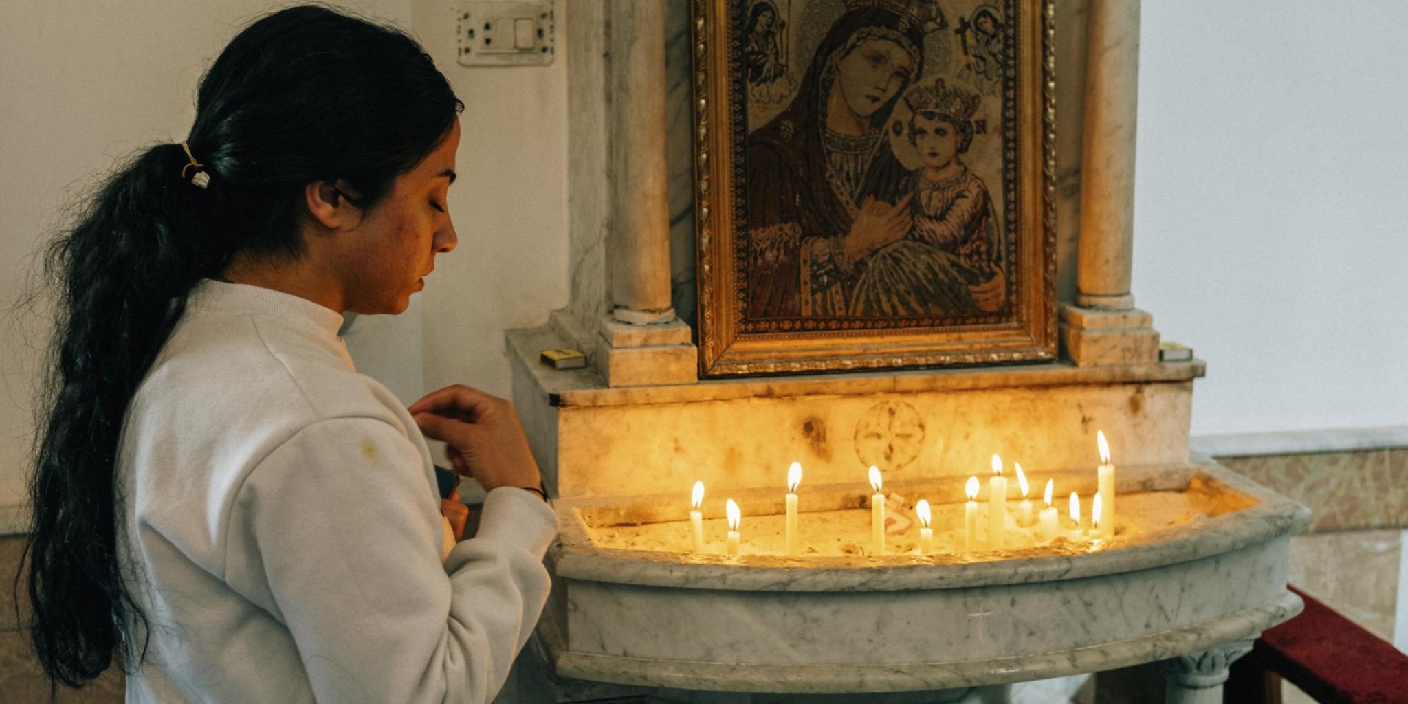 Ein Mädchen entzündet vor einer Ikone in der syrisch-katholischen Kathedrale  in Homs (Syrien) eine Kerze.